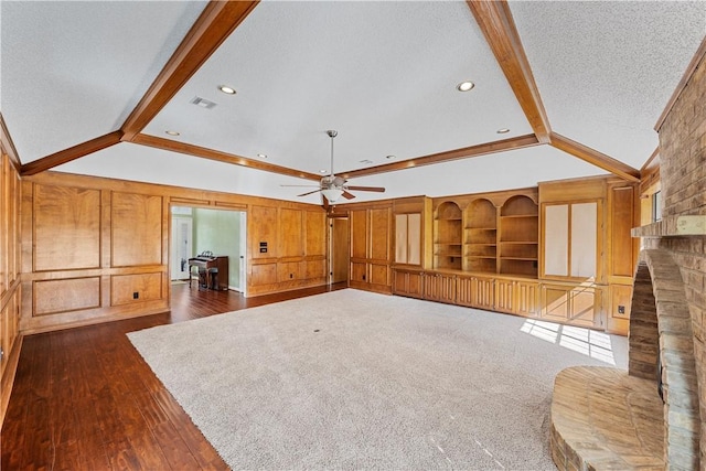 unfurnished living room featuring lofted ceiling with beams, a brick fireplace, ceiling fan, a textured ceiling, and dark hardwood / wood-style flooring