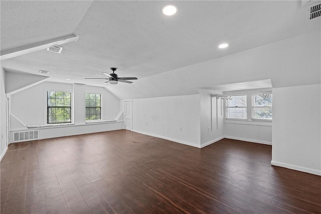 bonus room featuring a textured ceiling, ceiling fan, dark wood-type flooring, and vaulted ceiling