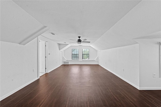 bonus room with a textured ceiling, lofted ceiling, ceiling fan, and dark hardwood / wood-style floors