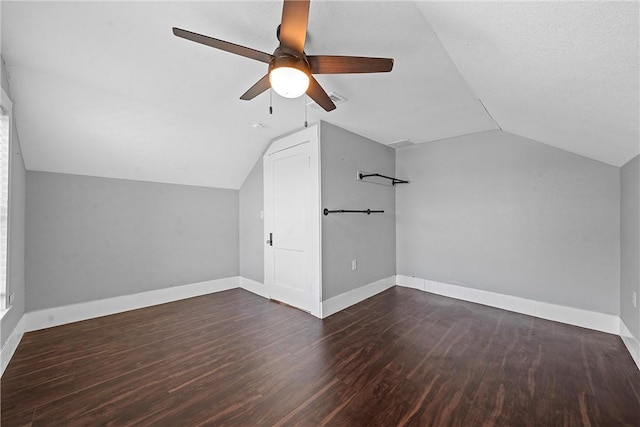 additional living space with a textured ceiling, vaulted ceiling, ceiling fan, and dark wood-type flooring