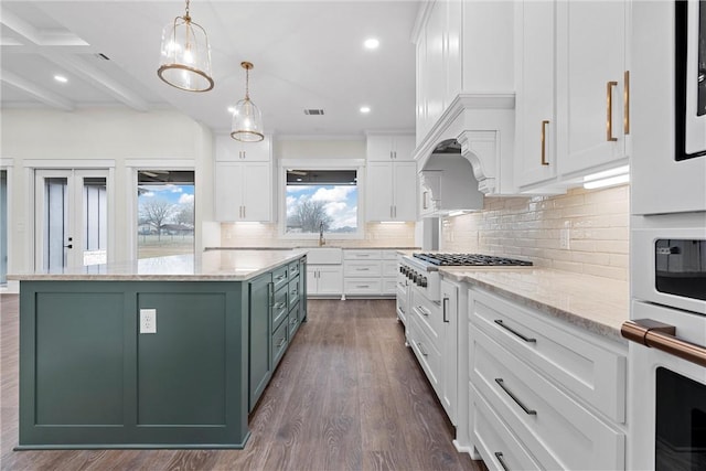 kitchen featuring sink, white cabinetry, a center island, light stone counters, and decorative light fixtures