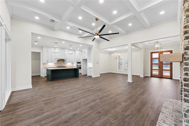 unfurnished living room featuring beam ceiling, ceiling fan with notable chandelier, coffered ceiling, and dark hardwood / wood-style floors