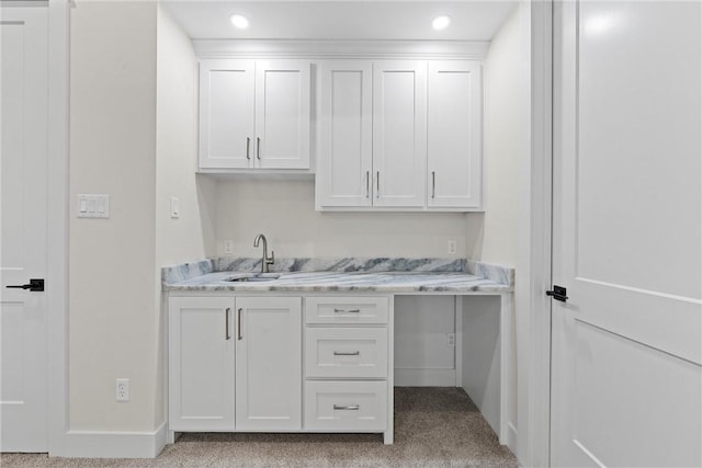 interior space featuring white cabinetry, light stone countertops, and sink