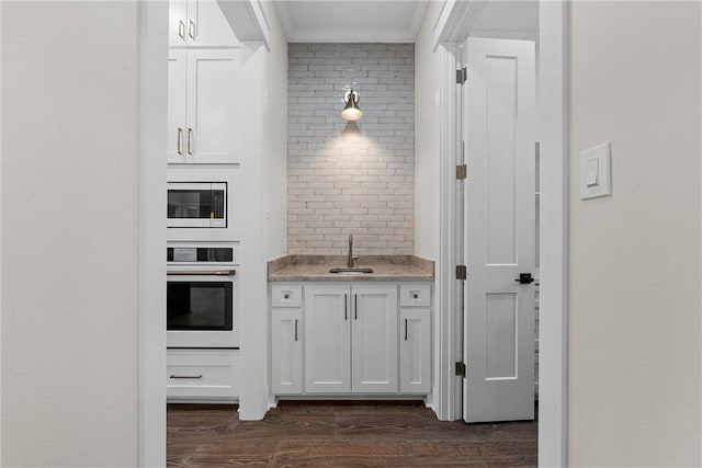 kitchen with white cabinets, dark wood-type flooring, stainless steel microwave, and oven