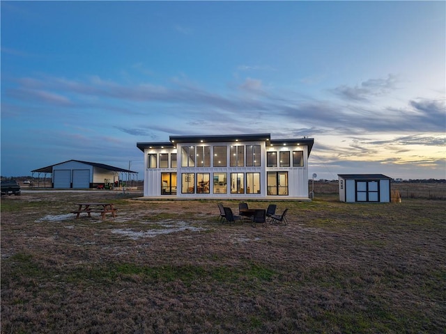 rear view of house featuring a garage, a sunroom, a storage shed, and an outbuilding