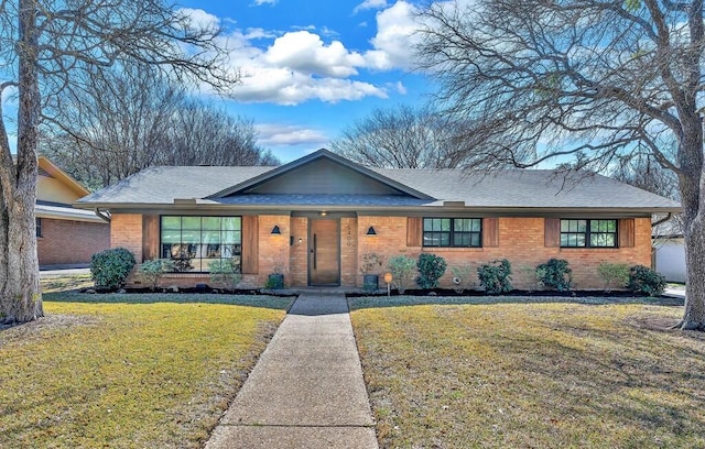 view of front of home featuring brick siding, roof with shingles, covered porch, and a front lawn