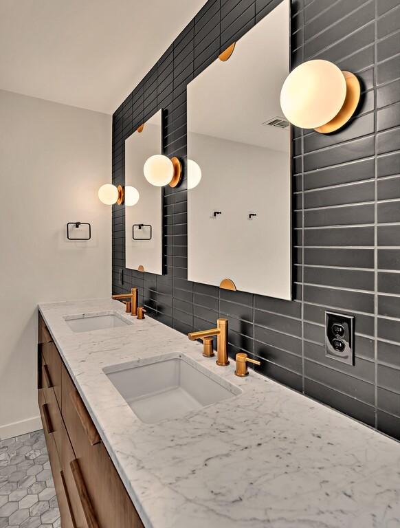 full bath featuring a sink, baseboards, tasteful backsplash, and double vanity