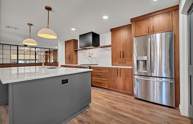 kitchen featuring light wood finished floors, visible vents, appliances with stainless steel finishes, brown cabinetry, and a sink