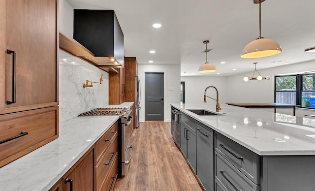 kitchen featuring a sink, tasteful backsplash, appliances with stainless steel finishes, brown cabinetry, and light wood finished floors