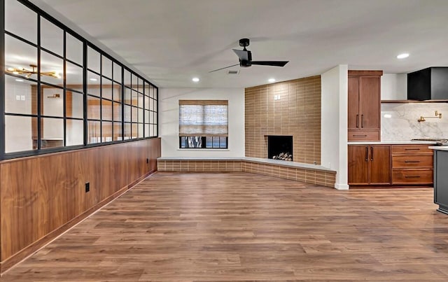 unfurnished living room featuring recessed lighting, a fireplace, wood finished floors, and a ceiling fan