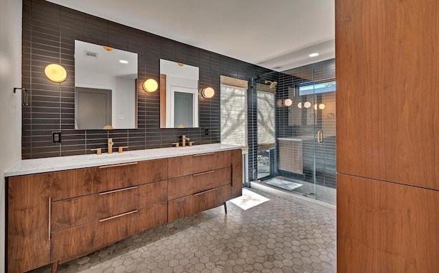 bathroom featuring double vanity, decorative backsplash, a stall shower, tile walls, and a sink