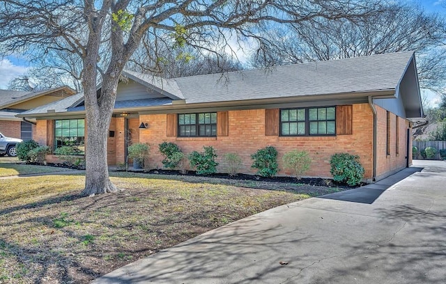 ranch-style home featuring brick siding and a shingled roof