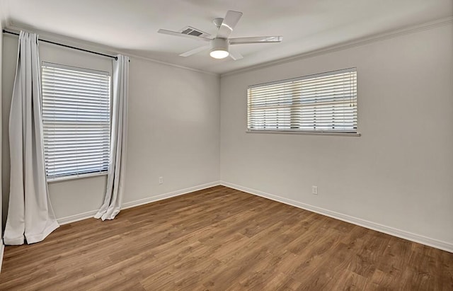 unfurnished room featuring visible vents, ceiling fan, baseboards, ornamental molding, and wood finished floors