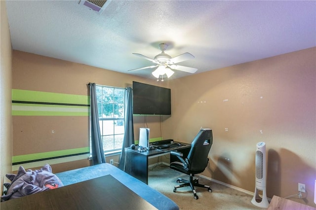 carpeted home office with a textured ceiling and ceiling fan