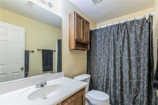 bathroom with a textured ceiling, vanity, and toilet