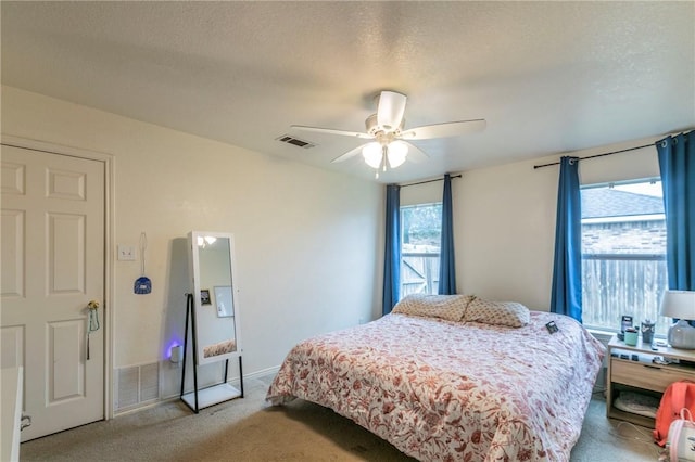 carpeted bedroom featuring ceiling fan and a textured ceiling