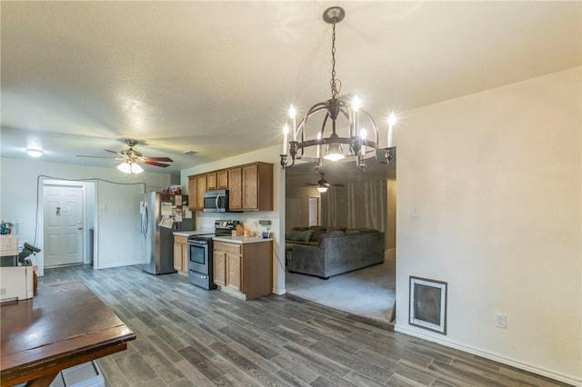 kitchen featuring pendant lighting, ceiling fan with notable chandelier, dark hardwood / wood-style flooring, and appliances with stainless steel finishes