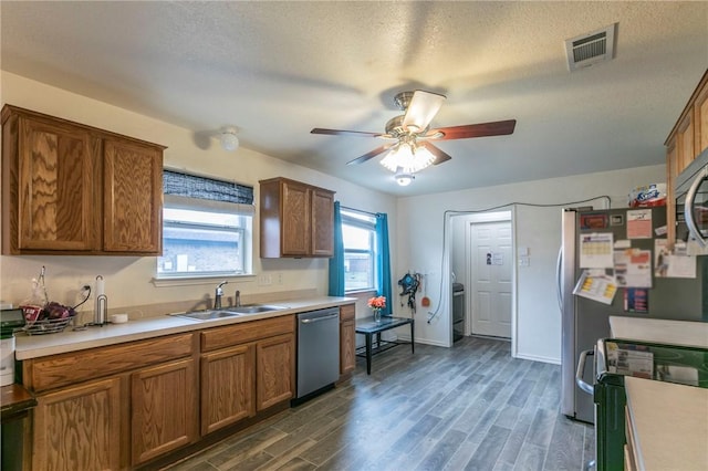 kitchen featuring dark wood-type flooring, sink, ceiling fan, a textured ceiling, and appliances with stainless steel finishes