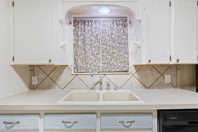 kitchen with white cabinetry, black dishwasher, sink, and backsplash