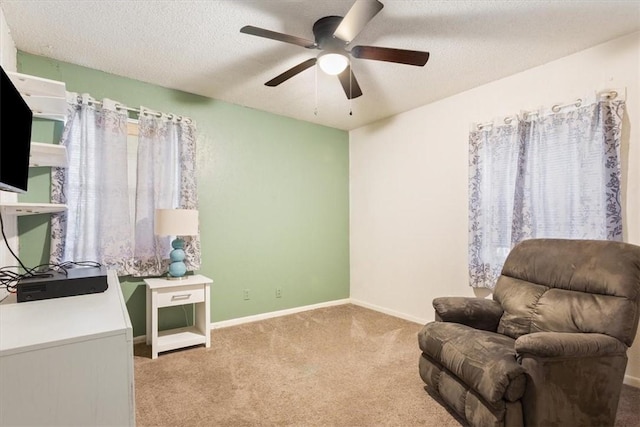 living area featuring ceiling fan, light colored carpet, and a textured ceiling