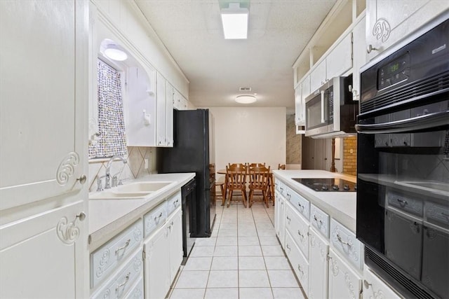 kitchen with tasteful backsplash, sink, white cabinets, light tile patterned floors, and black appliances