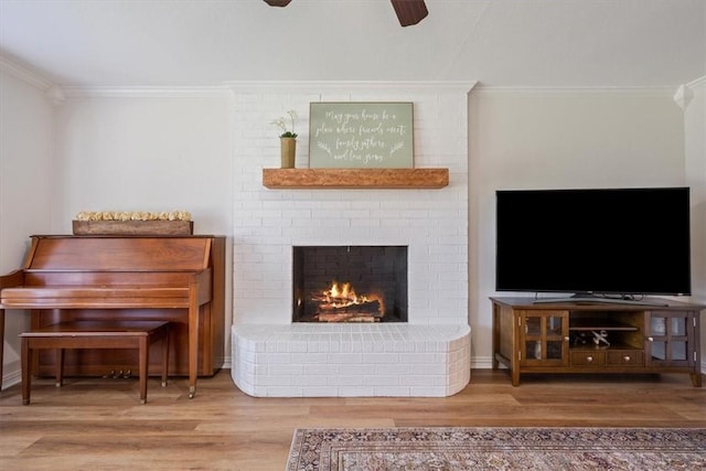 living room featuring crown molding, wood-type flooring, and a brick fireplace