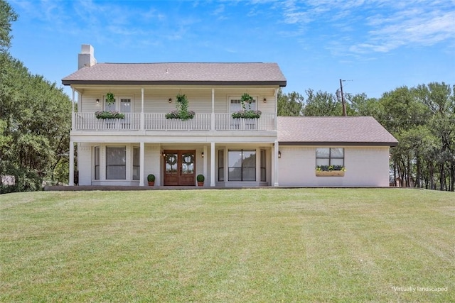 view of front facade featuring a balcony, a front lawn, and french doors