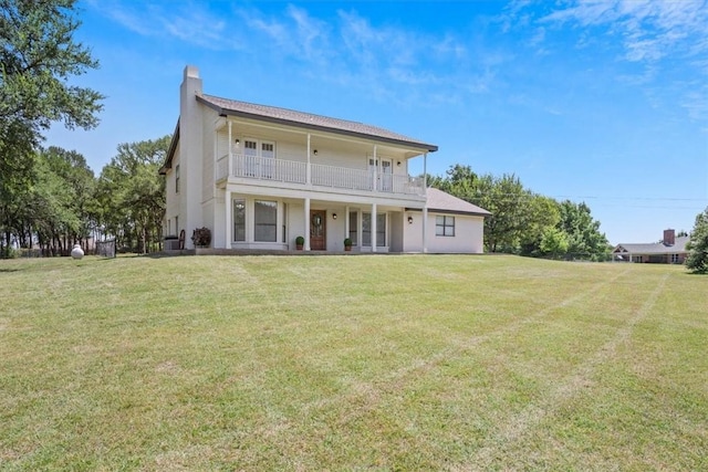 back of property with a balcony and a lawn