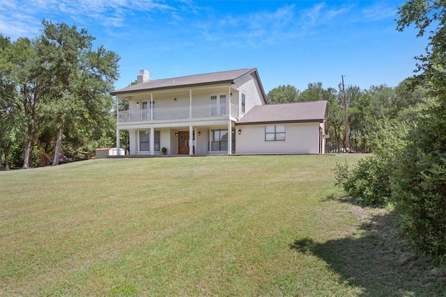 rear view of house featuring a yard and a balcony