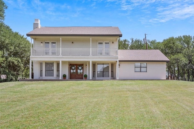 back of house with french doors, a balcony, and a lawn