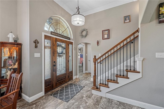 entrance foyer featuring a towering ceiling, crown molding, and french doors