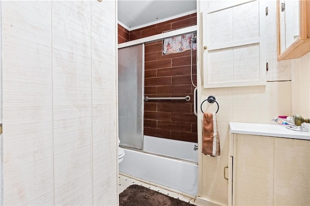 full bathroom featuring vanity, bath / shower combo with glass door, tile walls, and toilet