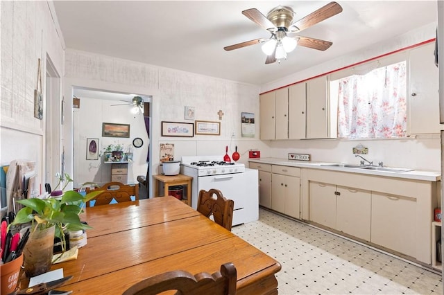 kitchen featuring white range with gas stovetop, cream cabinetry, and sink