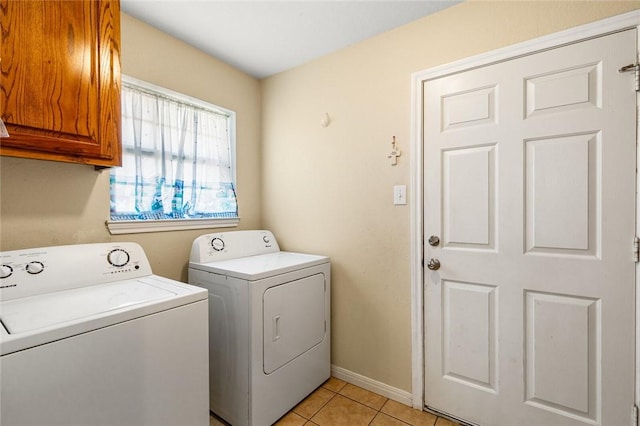 washroom with light tile patterned flooring, cabinets, and washing machine and clothes dryer