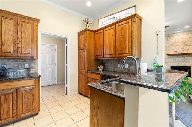 kitchen with sink, a kitchen breakfast bar, kitchen peninsula, dark stone counters, and light tile patterned flooring