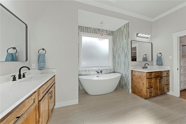 bathroom with a bath, vanity, an inviting chandelier, and ornamental molding