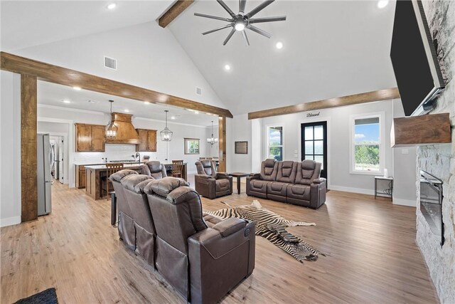 living room featuring beam ceiling, high vaulted ceiling, light hardwood / wood-style floors, and ceiling fan with notable chandelier