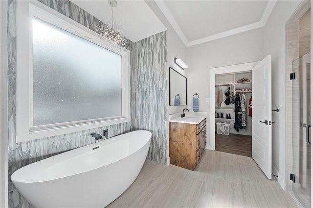 bathroom featuring plus walk in shower, a notable chandelier, vanity, tile walls, and hardwood / wood-style flooring