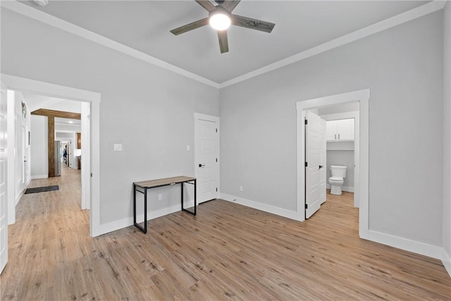 unfurnished bedroom with a walk in closet, light hardwood / wood-style flooring, ceiling fan, and crown molding