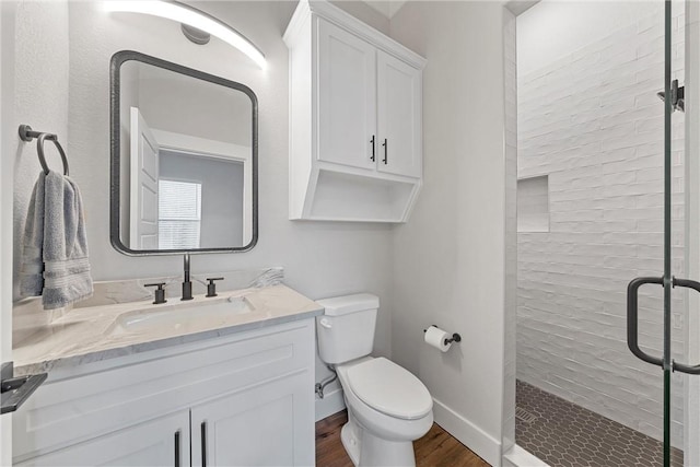 bathroom with hardwood / wood-style floors, vanity, toilet, and walk in shower