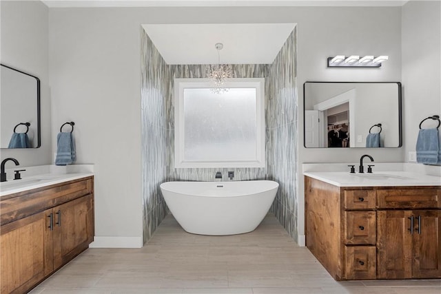 bathroom featuring a chandelier, a bath, vanity, and tile walls