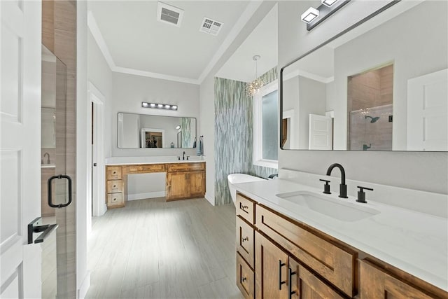 bathroom featuring vanity, hardwood / wood-style flooring, ornamental molding, a notable chandelier, and a shower with shower door