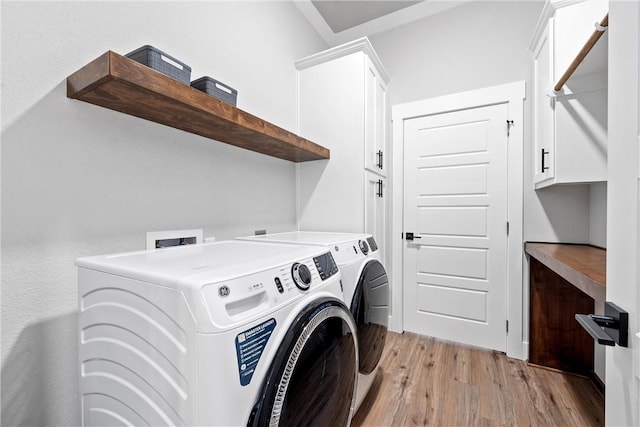 clothes washing area featuring cabinets, light wood-type flooring, and washer and clothes dryer