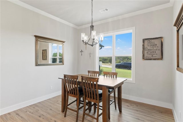 dining area featuring crown molding, light hardwood / wood-style floors, and a notable chandelier