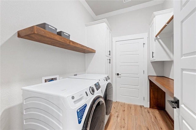 clothes washing area featuring separate washer and dryer, cabinets, and light hardwood / wood-style floors