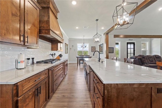 kitchen with a large island, light hardwood / wood-style floors, hanging light fixtures, and stainless steel gas cooktop