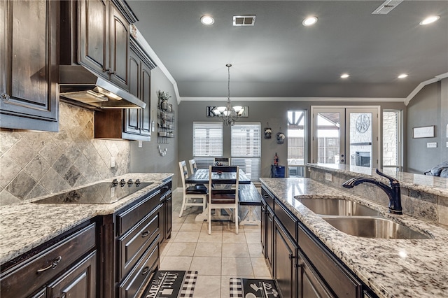 kitchen with ornamental molding, dark brown cabinets, black electric cooktop, sink, and a chandelier