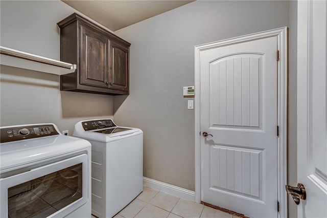 laundry area featuring washer and clothes dryer, light tile patterned flooring, and cabinets