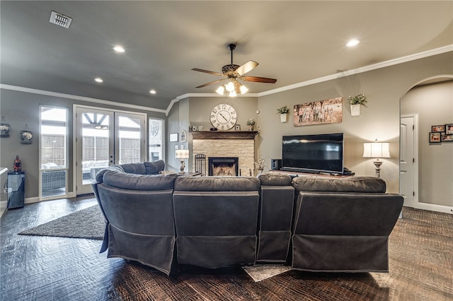 living room with a stone fireplace, ceiling fan, and ornamental molding