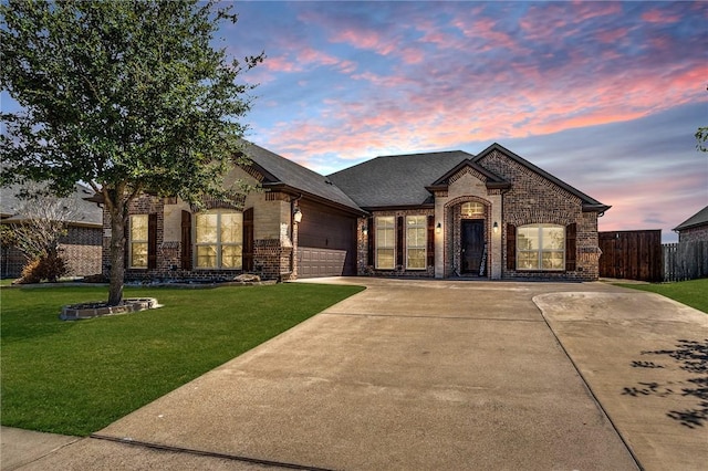 french country home featuring a lawn and a garage